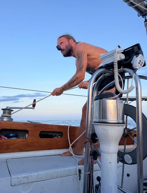 Dillon working a winch on deck at dusk